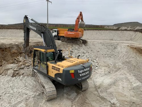 Seydiler trafo merkezi sahasında Tuğra Hafriyat’ın riperli Volvo ekskavatörü, arka planda Hitachi ekskavatör ve damperli kamyon görülüyor.