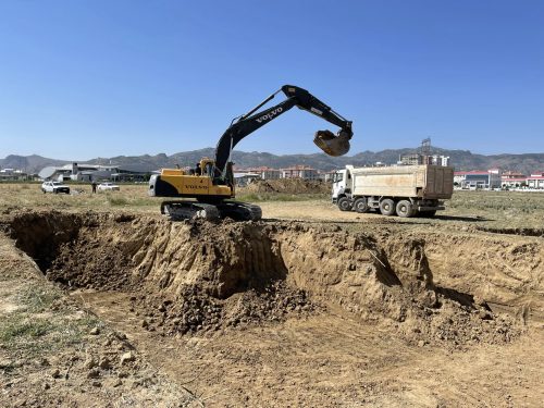 Uydukent konut projesi temel kazısı alanında, kazı kenarında çalışan Volvo paletli ekskavatörümüz ve yanında bekleyen beyaz damperli kamyonumuz.