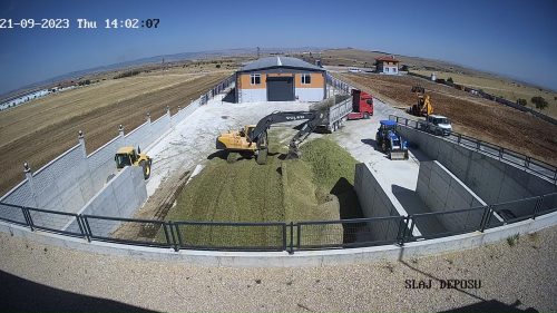 Uzuntepe Tarım çiftliğinde mısır silajı sevkiyatı, paletli ekskavatör ve silindirle silaj çiğneme ve sıkıştırma işlerinin güvenlik kamerası görüntüsü.